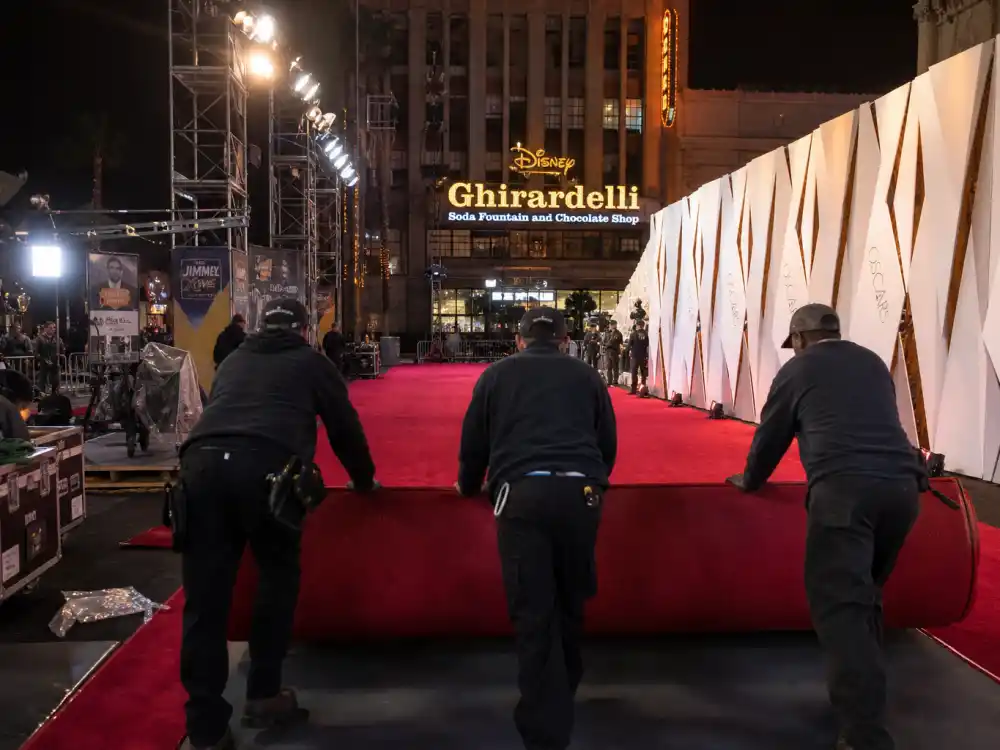 Red carpet installation crew rolling carpet outside theater for how much do the Oscars cost to produce arrivals infrastructure and broadcast setup