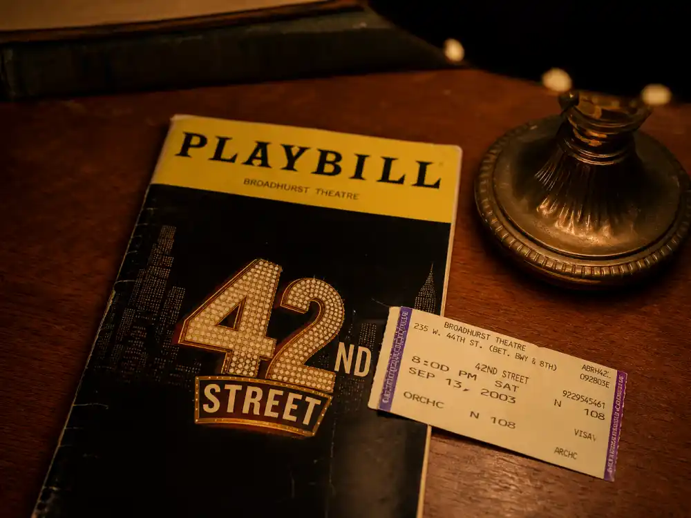 Broadway playbill on desk evoking how old is Ariana Grande early career when she performed on stage as a teenager in New York