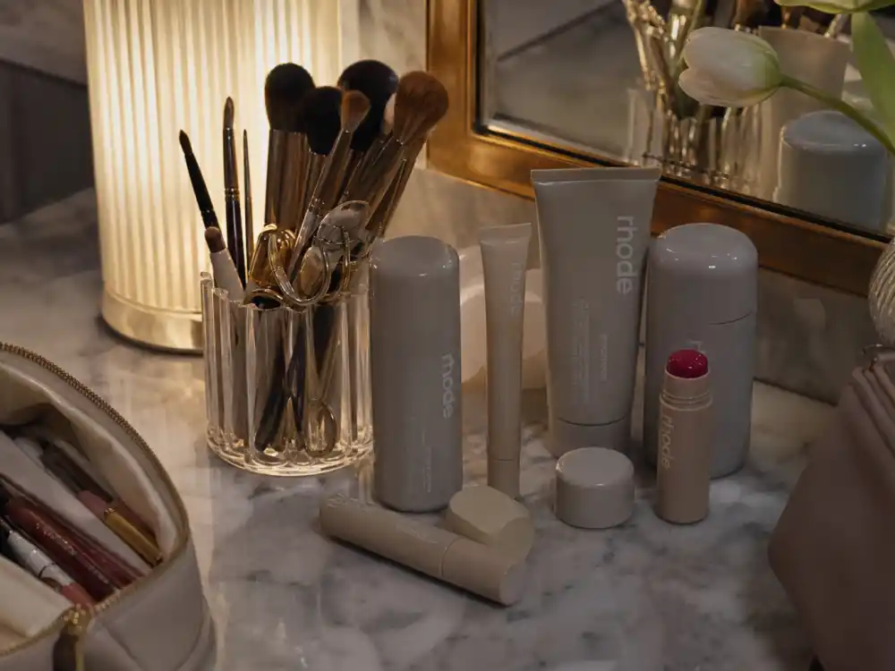 Luxury beauty vanity with skincare products reflecting how old is Hailey Bieber career arc from runway modeling to Rhode skincare founder status