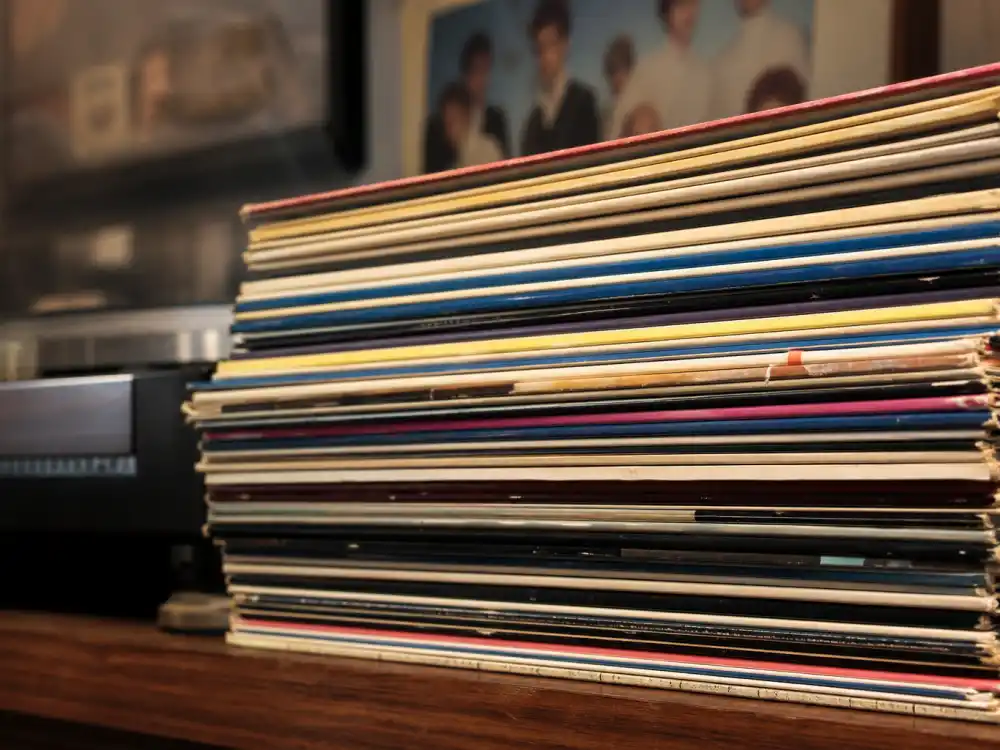 Vinyl record stack on shelf reflecting how old is Harry Styles One Direction era when the boy band dominated global charts in his late teens and early twenties