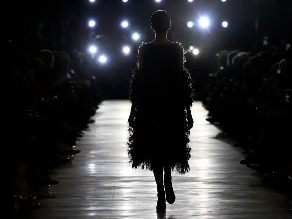 Fashion runway with spotlights reflecting how old is Kendall Jenner career arc from reality television breakout to highest-paid runway model status
