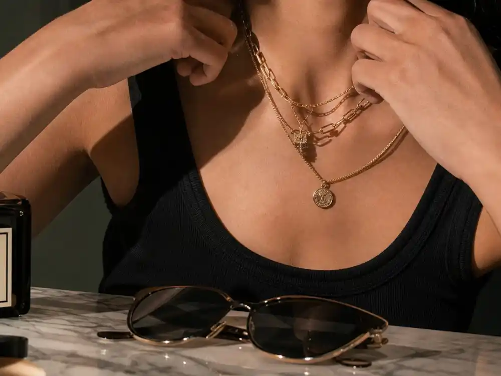 Layered gold chains and 90s retro sunglasses finishing how to dress like Bella Hadid model off duty accessory elevation