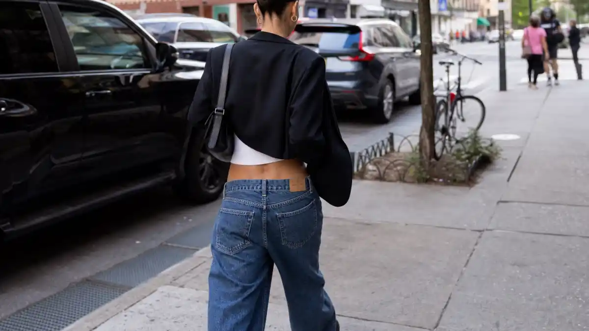 How to dress like Bella Hadid model off duty — low-rise wide jeans cropped tank oversized black blazer and gold hoops on NYC sidewalk seen from behind