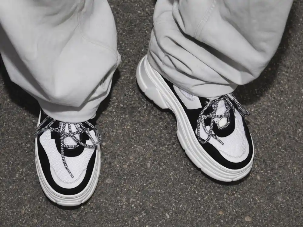 Chunky white platform sneakers with baggy pant cuffs illustrating how to dress like Billie Eilish oversized style footwear discipline