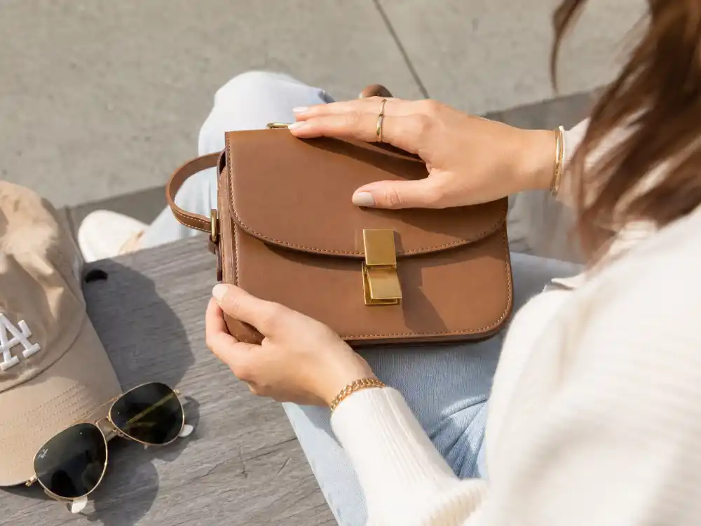 Tan crossbody bag aviator sunglasses and gold hoops finishing how to dress like Gigi Hadid street style accessory layer