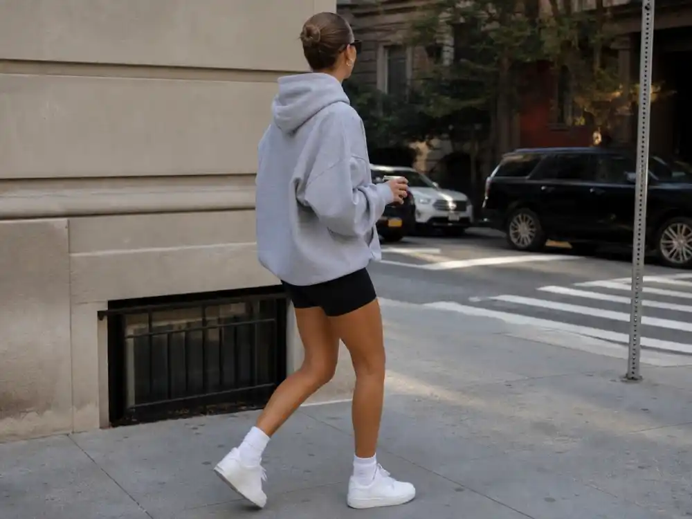 Oversized grey hoodie and black biker shorts illustrating how to dress like Gigi Hadid street style sports-luxe formula