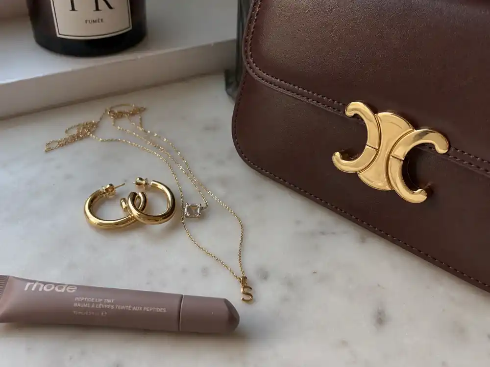 Gold hoops Rhode lip balm and structured handbag accessories for how to dress like Hailey Bieber off duty clean girl finish