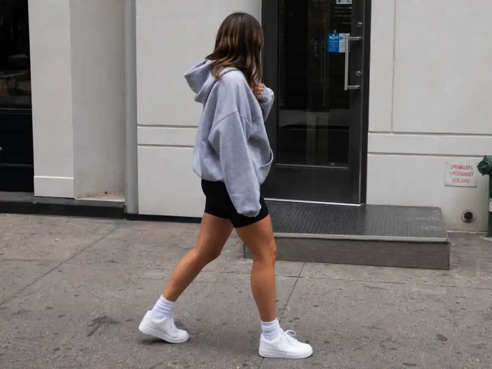 Oversized grey hoodie with black biker shorts showing how to dress like Kim Kardashian casual athleisure proportion