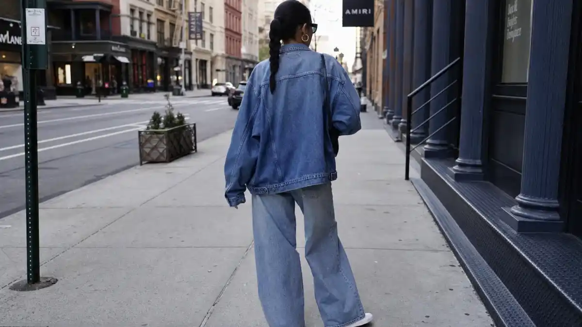 How to dress like Rihanna on a budget — oversized denim jacket wide-leg jeans and white sneakers on NYC sidewalk seen from behind