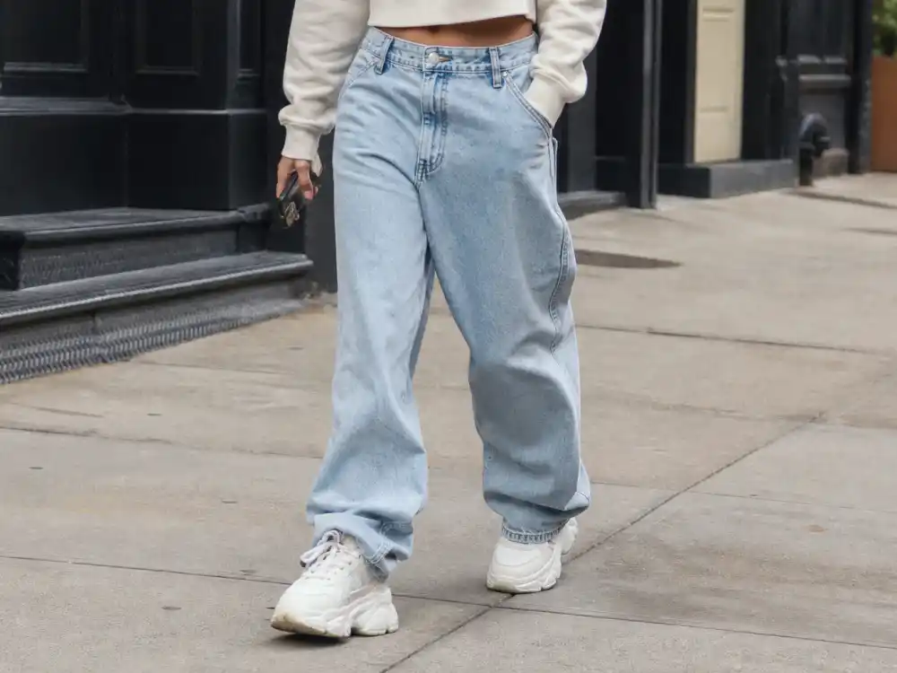 White chunky sneakers with baggy jeans illustrating how to dress like Rihanna on a budget street footwear