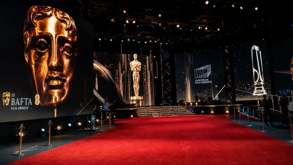 International award shows Americans should know — global film trophies including BAFTA mask and Oscar statuette on a dramatic awards ceremony stage