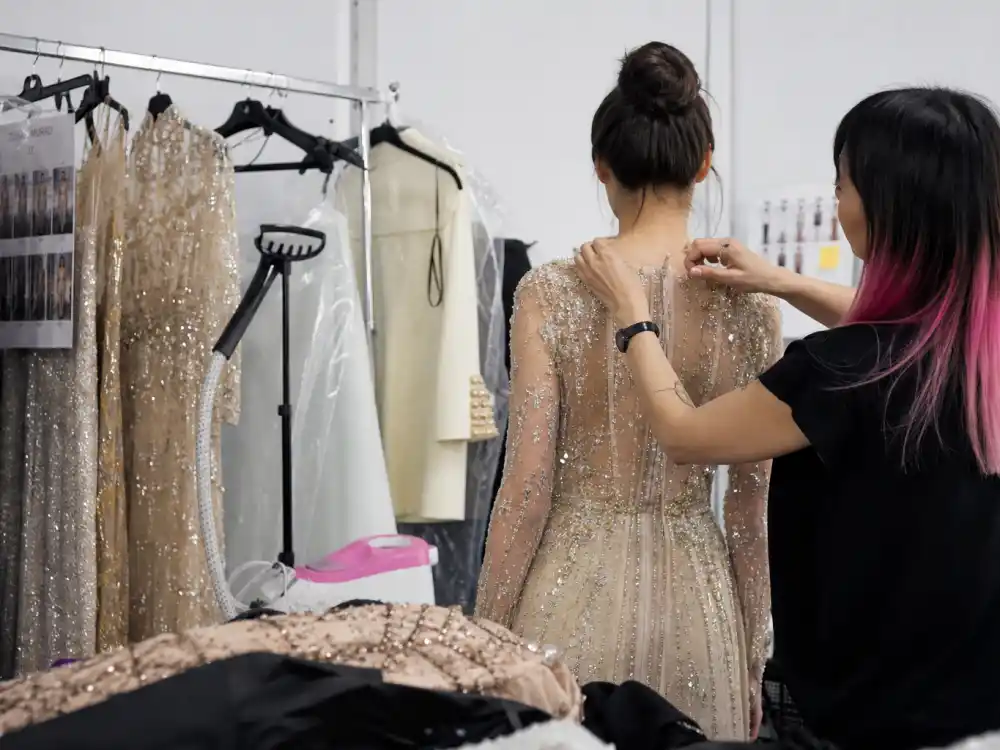 Backstage styling suite behind Irene Kim celebrity stylist fashion with garment racks steamer and final look adjustments before fashion show