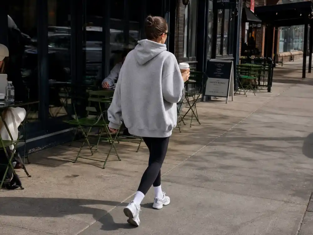 Grey hoodie black leggings and white sneakers on NYC coffee run showing Irina Shayk street style NYC off-duty athleisure