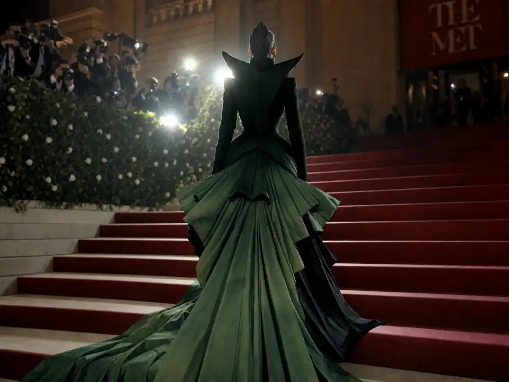 Met Gala museum steps at night with anonymous figure from behind in sculptural green couture gown under paparazzi flash for Jason Bolden celebrity stylist red carpet Met moments