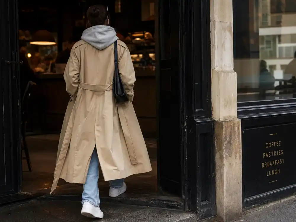 Trench coat over hoodie and straight jeans showing Kaia Gerber model off duty style runway-to-sidewalk transition