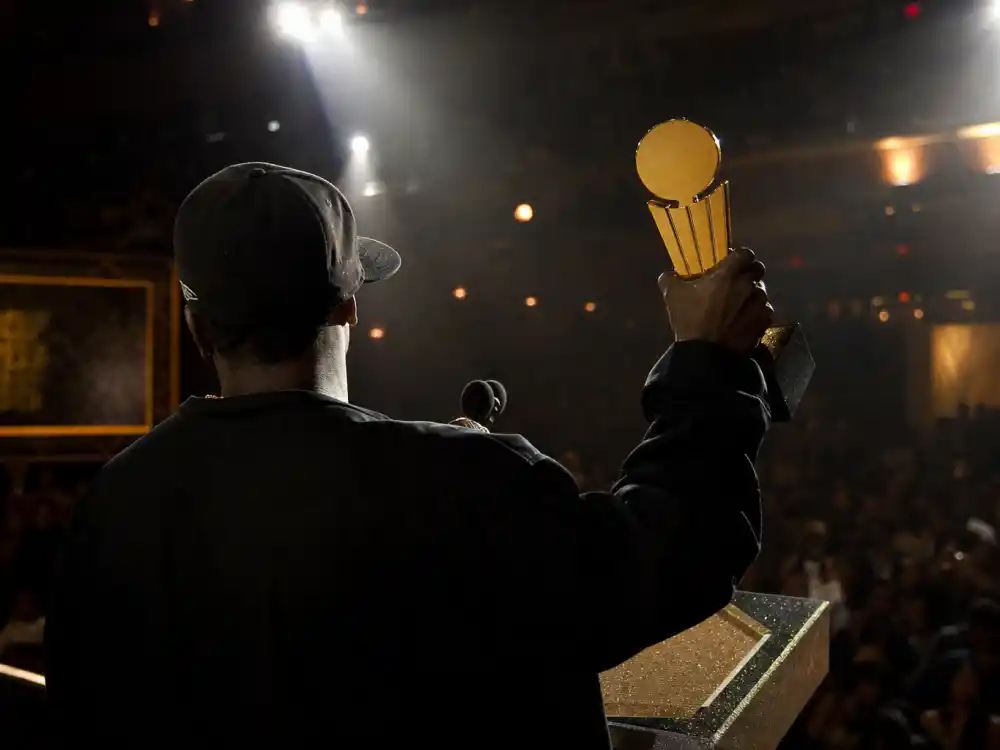 Producer silhouette from behind at awards podium holding golden trophy evokes Kanye West Grammy moments controversies early wins era at the 2004 ceremony