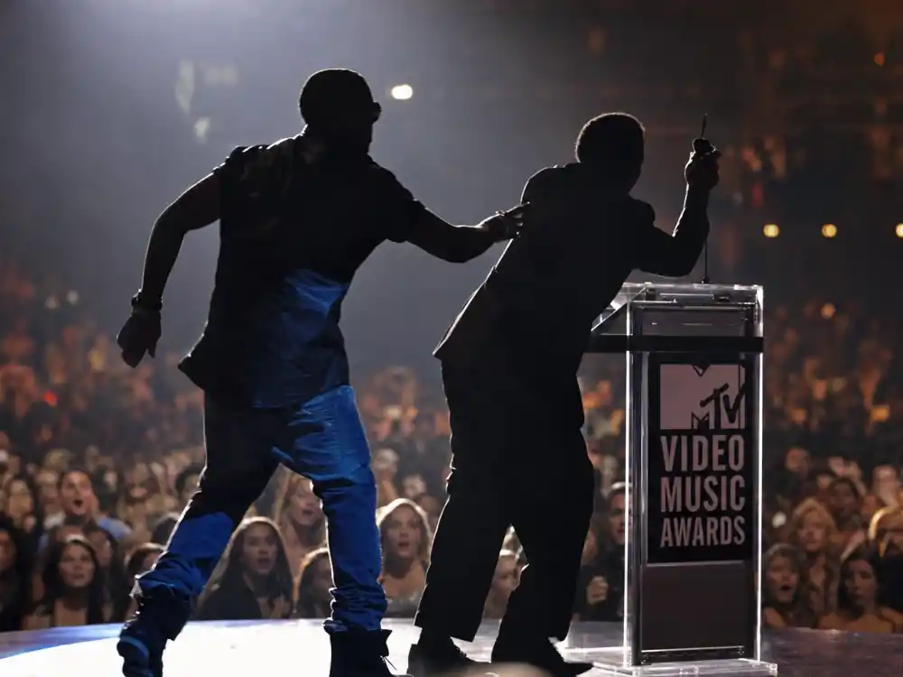 Live MTV VMA stage interruption silhouettes illustrate the Kanye West Taylor Swift VMA moment explained when one artist storms the podium during another winner speech