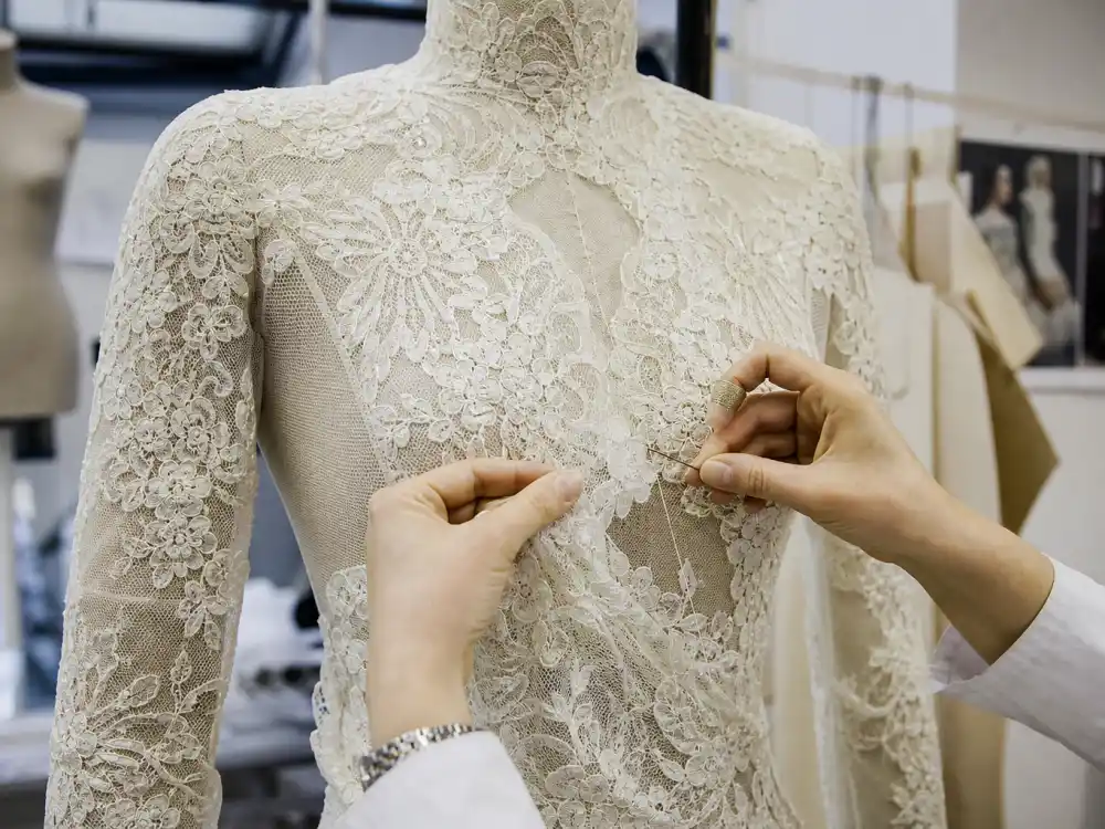 Sarah Burton Alexander McQueen atelier hands stitching ivory lace onto Kate Middleton wedding dress Alexander McQueen long-sleeve bodice
