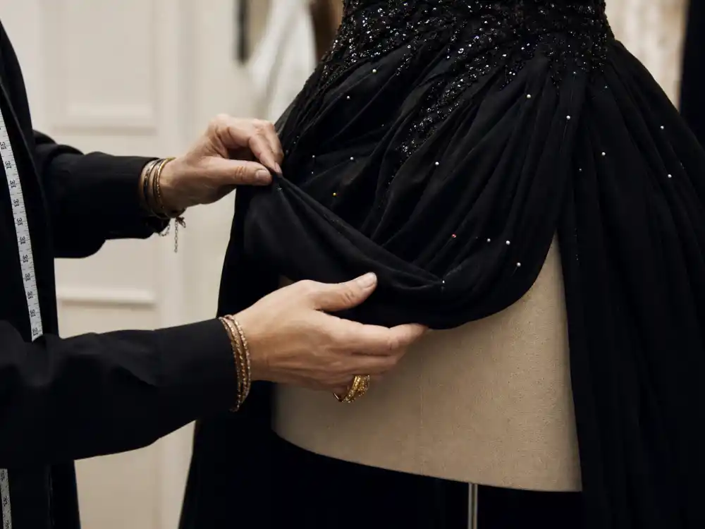 Stylist hands adjusting couture gown hem on dress form during fitting session demonstrating tailoring discipline from the Kate Young celebrity stylist guide