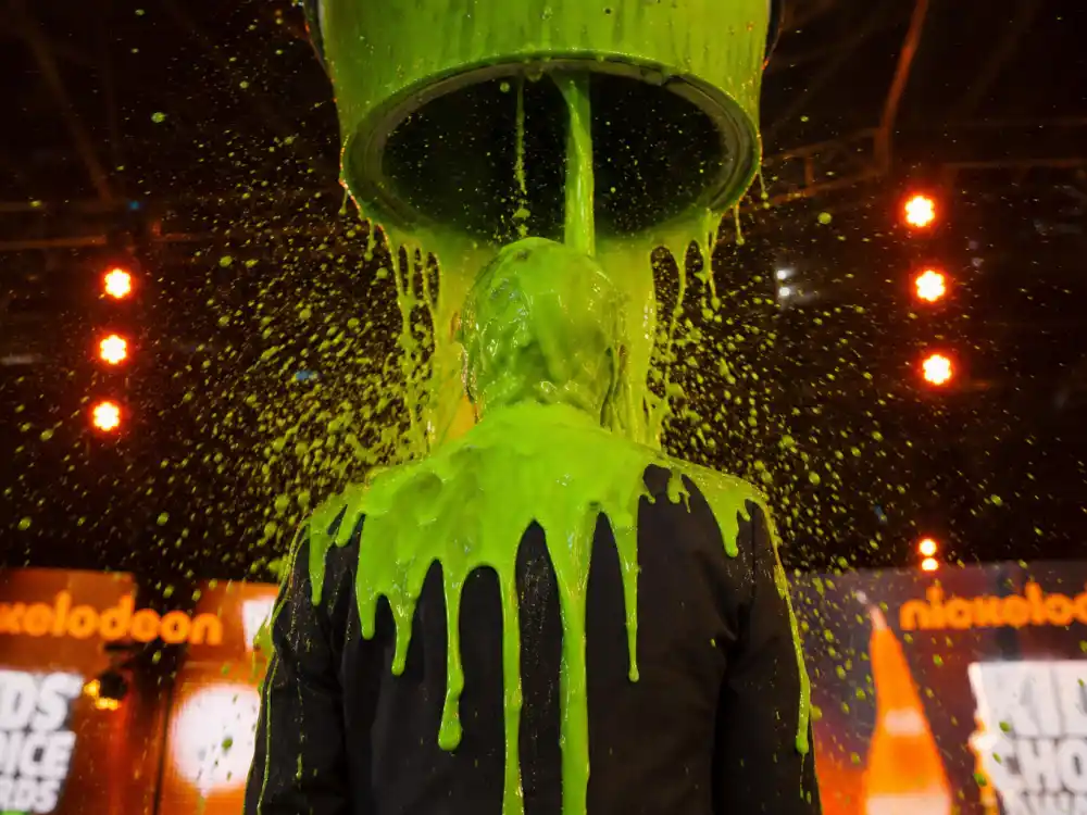 Anonymous presenter silhouette slimed with green goo at Kids Choice Awards slime history first celebrity dunking ceremony