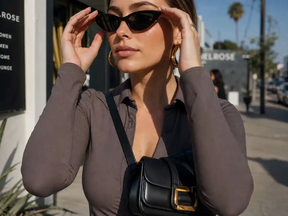 Cat-eye sunglasses gold hoops and structured crossbody bag finishing LA celebrity street style looks accessory layer