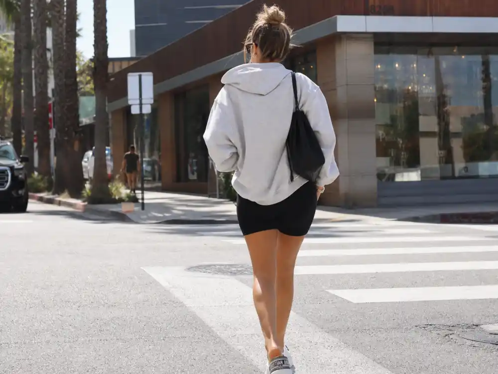 Gray hoodie biker shorts and designer slides illustrating LA celebrity street style looks athleisure rotation