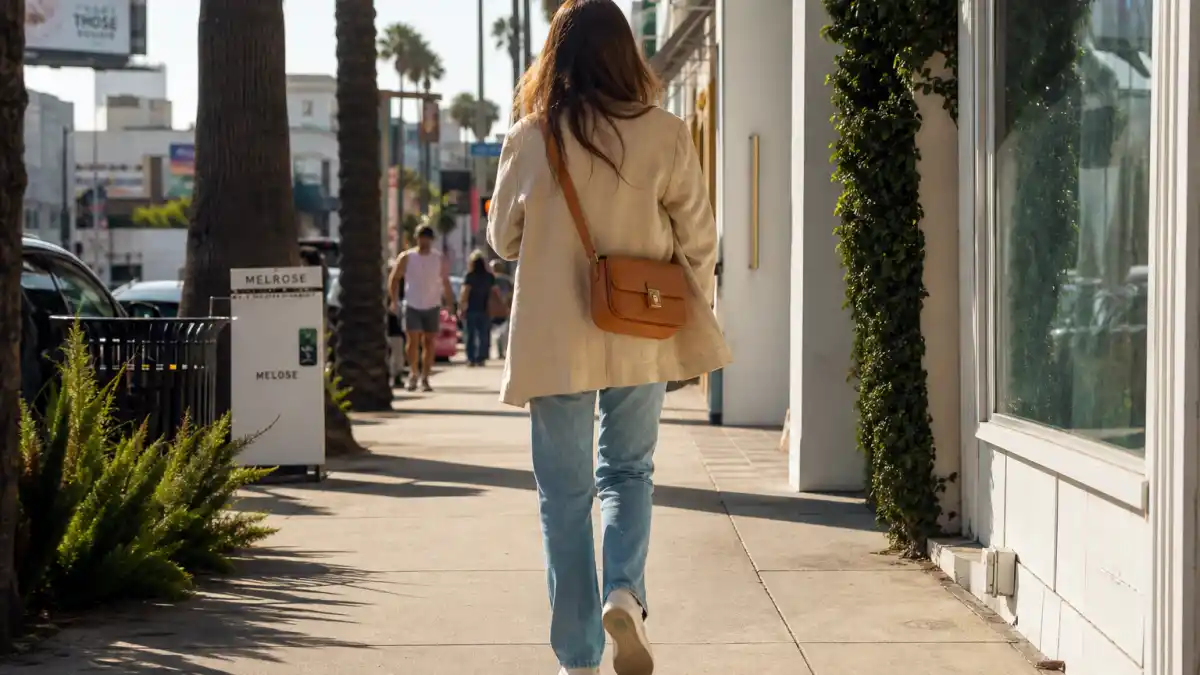 LA celebrity street style looks — oversized beige blazer straight-leg jeans and white sneakers on Melrose Avenue sidewalk seen from behind