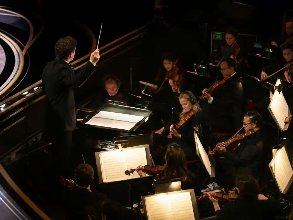 Orchestra conductor raising a baton to cue play-off music during some of the longest Oscar speeches ever at the Academy Awards