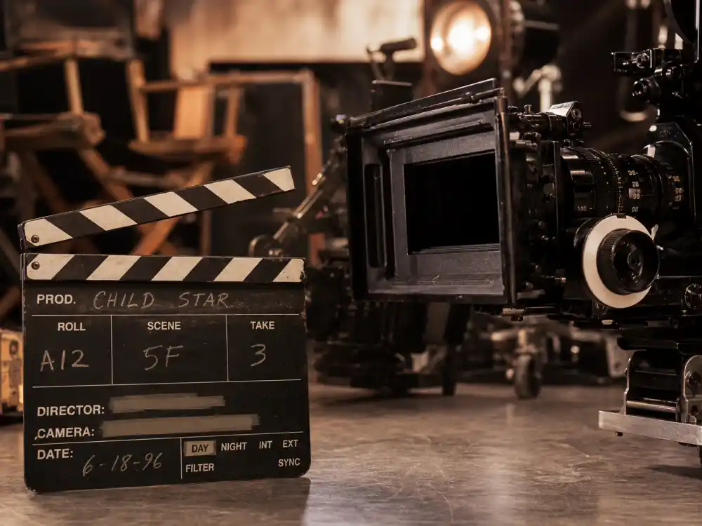 A film clapperboard and camera on set representing the Macaulay Culkin child star blockbuster era