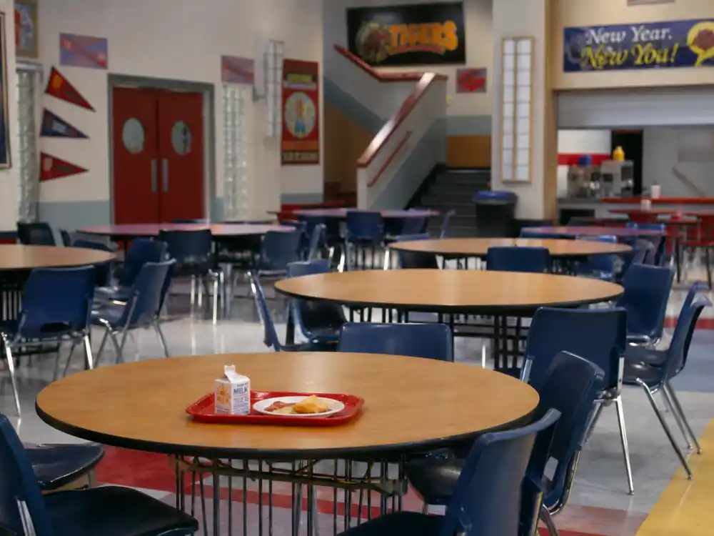 A 1990s high school cafeteria evoking Mark-Paul Gosselaar as Zack Morris on Saved by the Bell