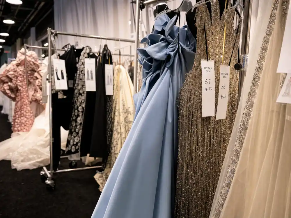 Haute couture evening gowns on rolling racks in designer showroom aisle showing luxury construction behind Met Gala best dressed all time atelier preparation