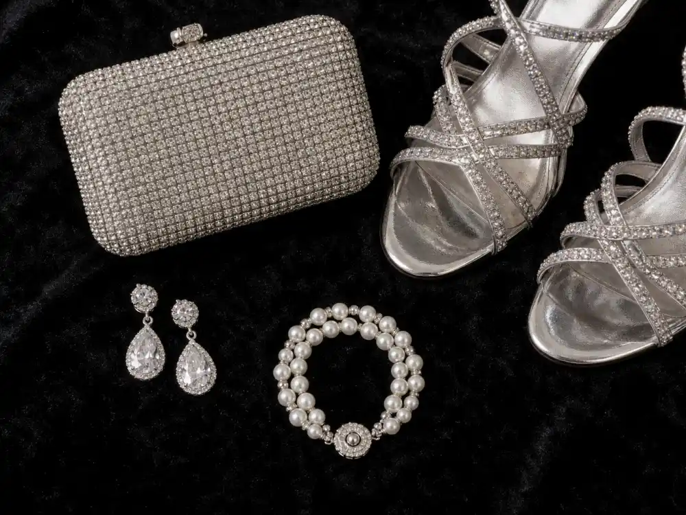 Diamond drop earrings crystal minaudiere strappy silver heels and pearl bracelet flat lay completing accessory stacking for Met Gala celebrity fashion 2026 evening looks