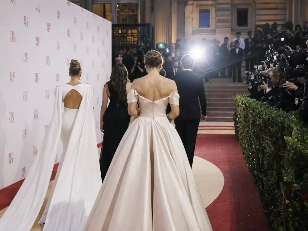 Met Gala red carpet at Metropolitan Museum entrance with step-and-repeat backdrop and anonymous figures from behind defining most iconic Met Gala looks ever arrival moments