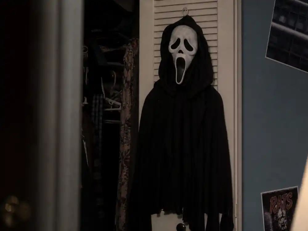 Horror movie mask and robe in dim bedroom for Neve Campbell Scream Sidney Prescott slasher icon fame