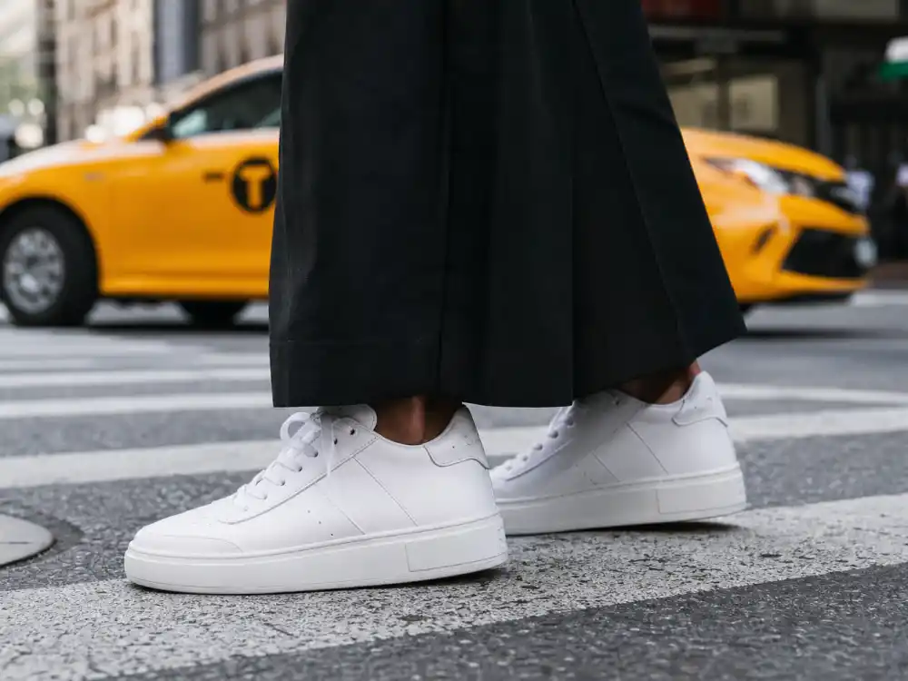 Pristine white leather sneakers on NYC crosswalk defining NYC celebrity street style trends elevated casual footwear proportion