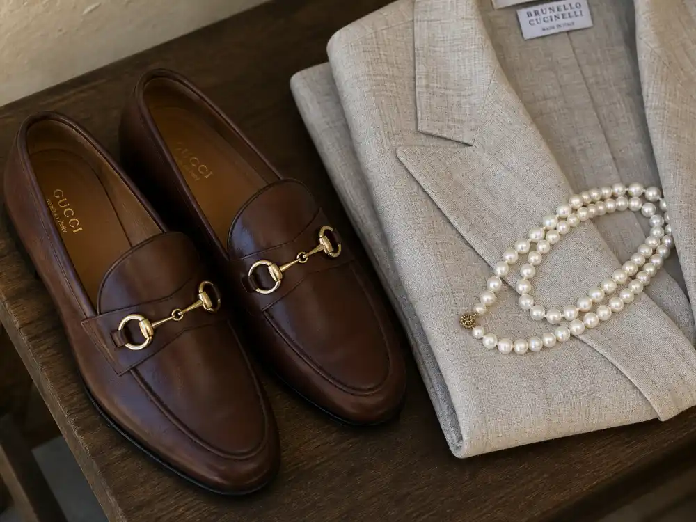 Brown penny loafers with gold horse-bit detail beside linen blazer and pearls finishing old money aesthetic celebrity style accessory rules