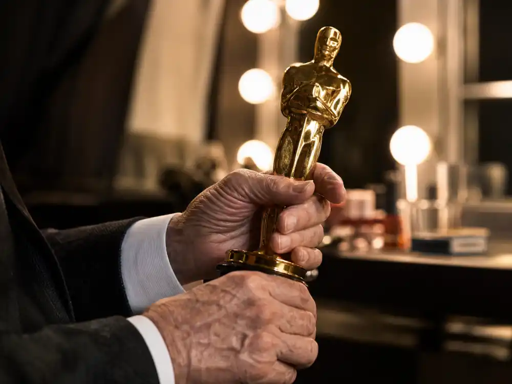 Elderly hands holding a golden statuette symbolizing late-career triumphs among the oldest Oscar winners in history