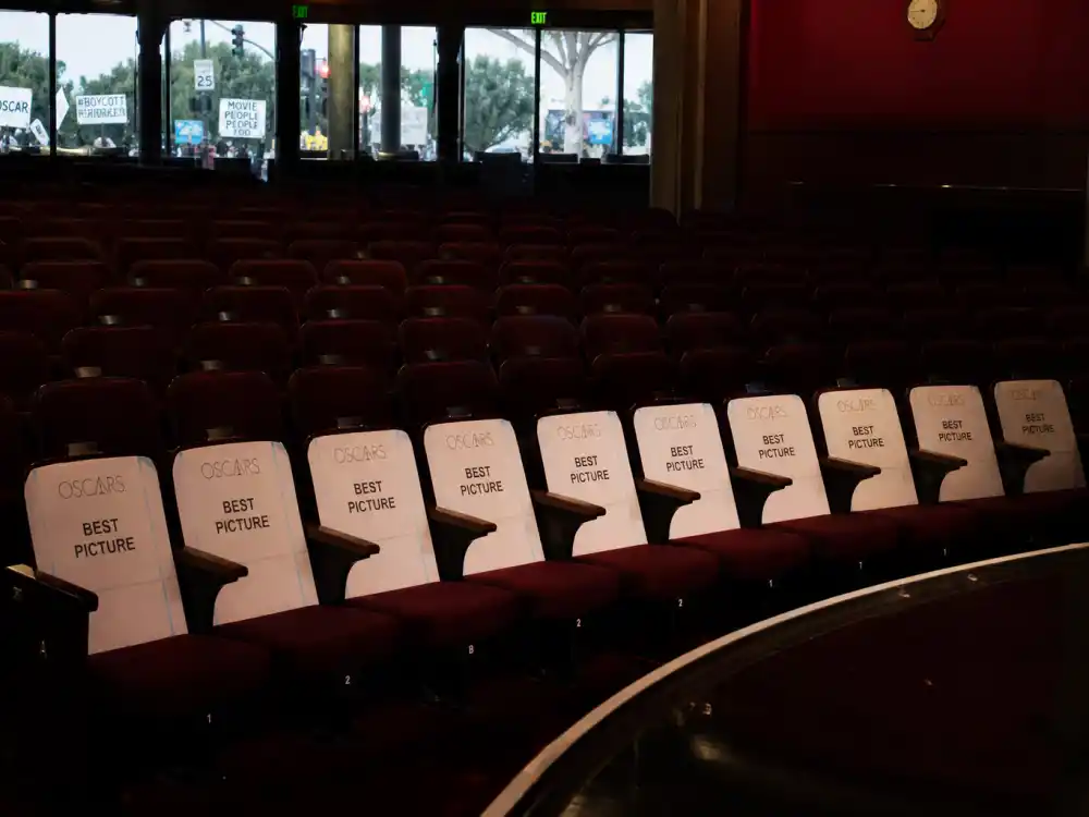 Vacant Academy Awards front-row seats with protest signs outside glass doors symbolize boycott pressure central to OscarsSoWhite controversy explained