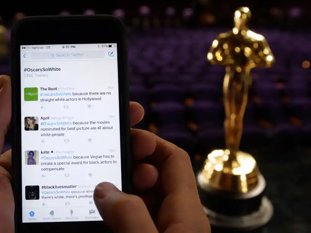 Smartphone screen trending OscarsSoWhite hashtag beside empty Oscar theatre seats shows how social media amplified OscarsSoWhite controversy explained globally