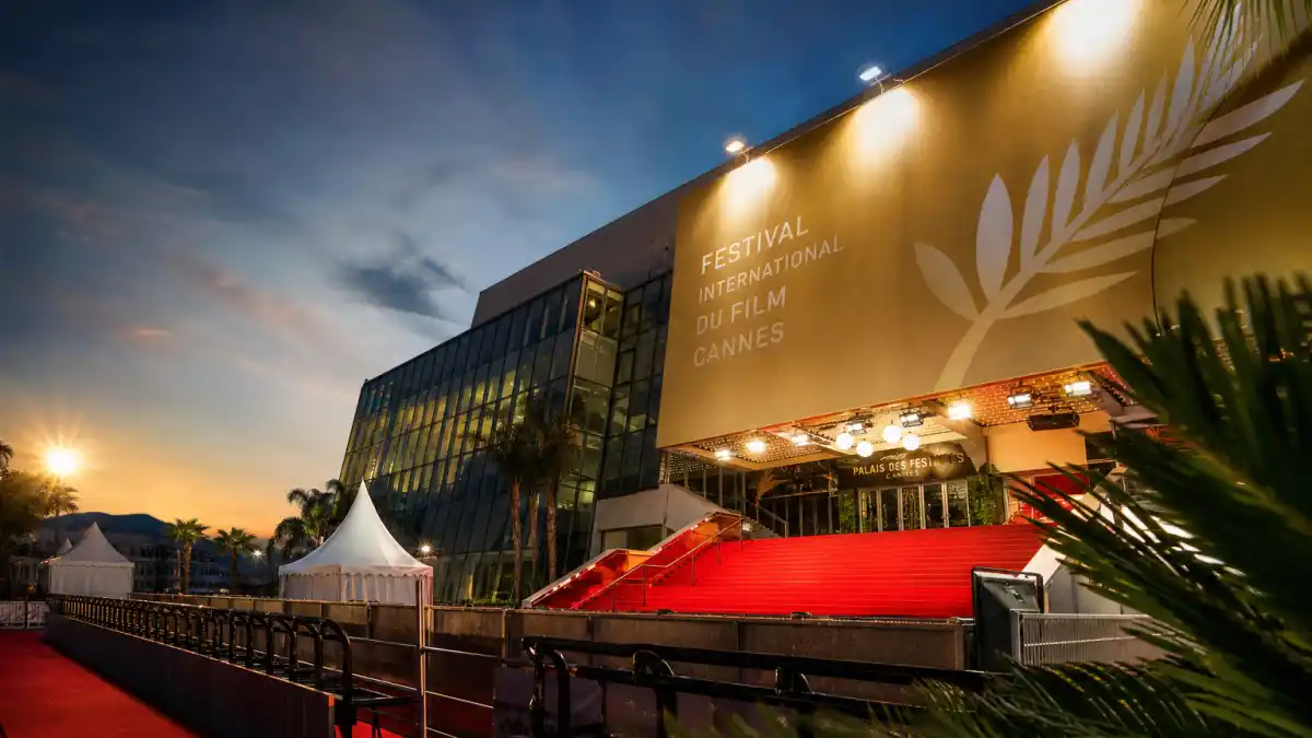 Palme d'Or winners list by year — Palais des Festivals red carpet and golden palm banner at dusk evoking Cannes Film Festival history