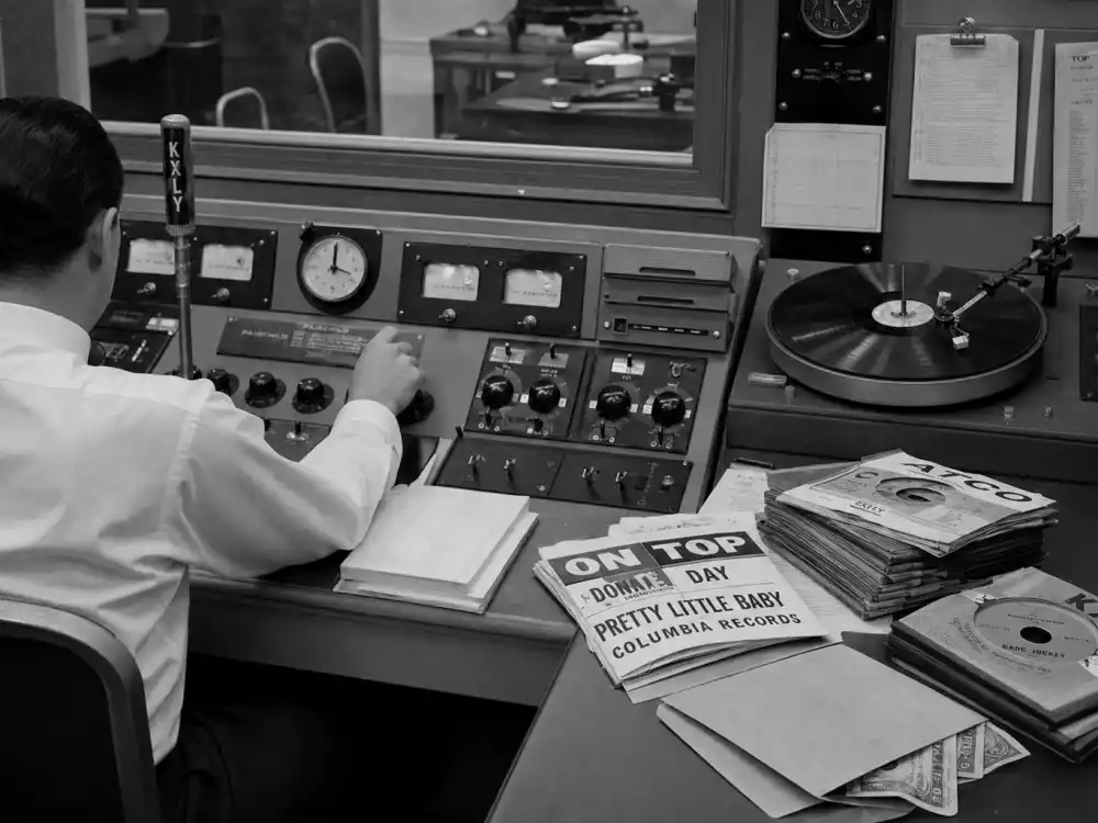 1950s radio control room with vinyl stacks illustrates payola and Grammy voting controversies — how labels once paid for airplay before Grammy peer ballots