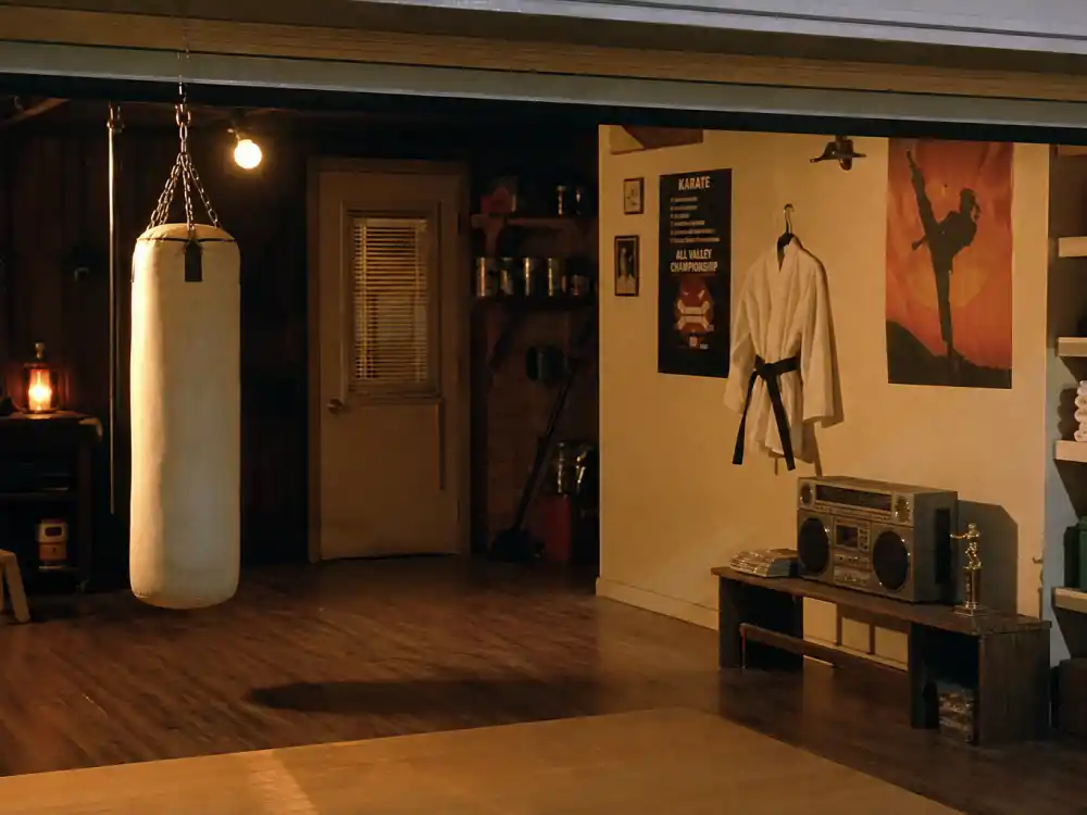 A 1980s suburban garage karate training space evoking Ralph Macchio Karate Kid Daniel LaRusso era