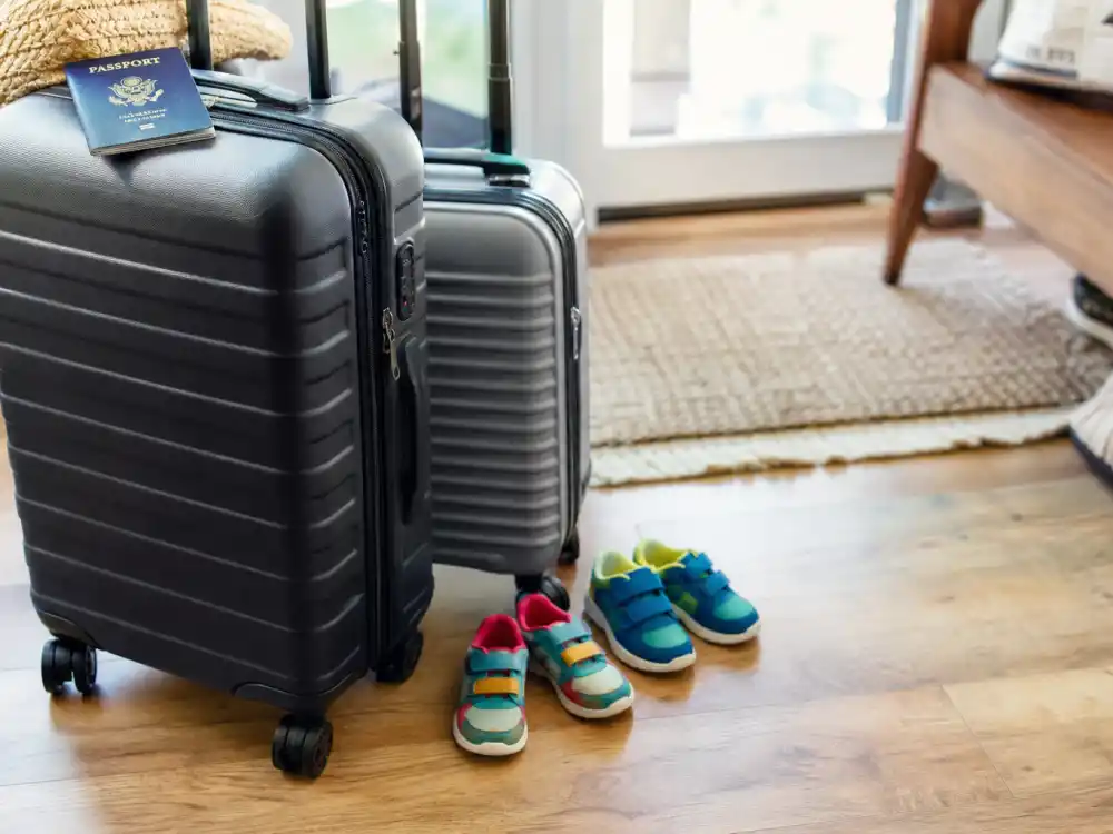 Family travel suitcases with kids sneakers in Rihanna family life Barbados and LA — dual-coast packing rhythm between Barbados visits and LA nursery months
