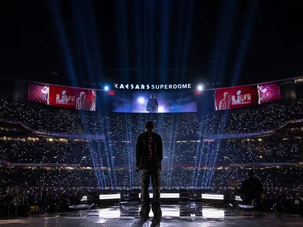Super Bowl halftime stage from behind with performer silhouette in Rihanna maternity leave comeback timeline — February 2023 second pregnancy bump debut