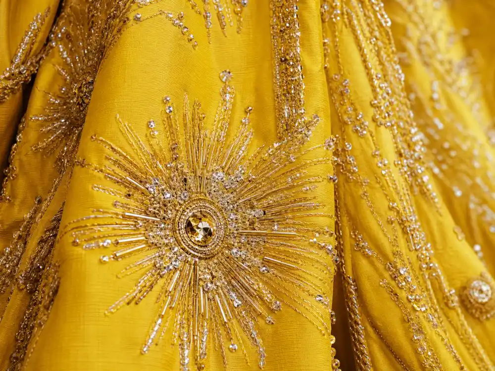 Intricate gold sunburst embroidery on yellow silk faille defining the Rihanna yellow Met Gala cape dress textile signature
