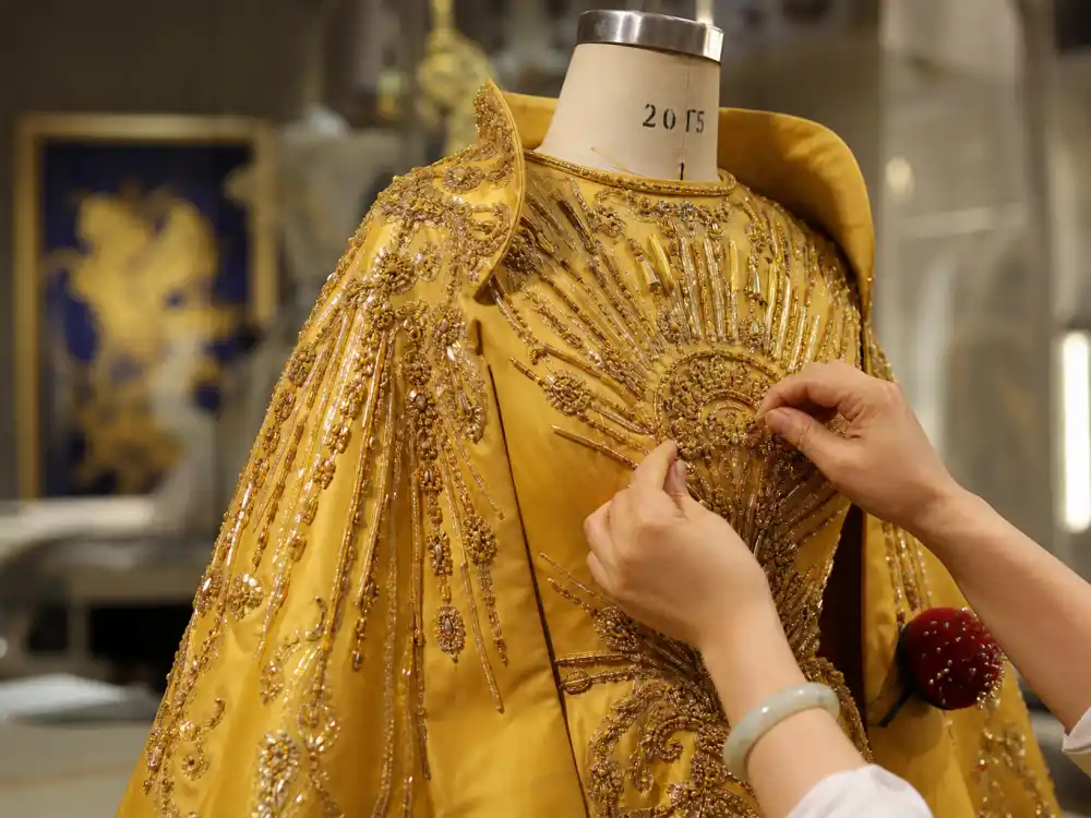 Guo Pei atelier craftsmanship behind the Rihanna yellow Met Gala cape dress — golden silk faille and sunburst embroidery on couture dress form