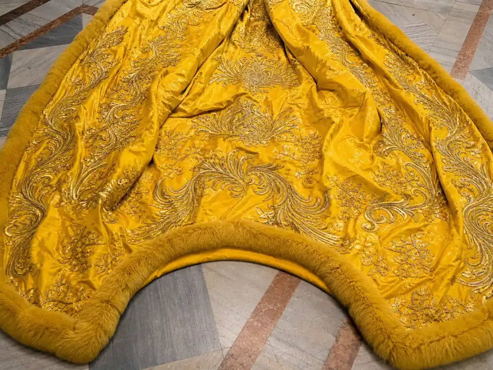 Cathedral-scale golden-yellow couture train spread across marble floor — the dramatic volume central to the Rihanna yellow Met Gala cape dress spectacle