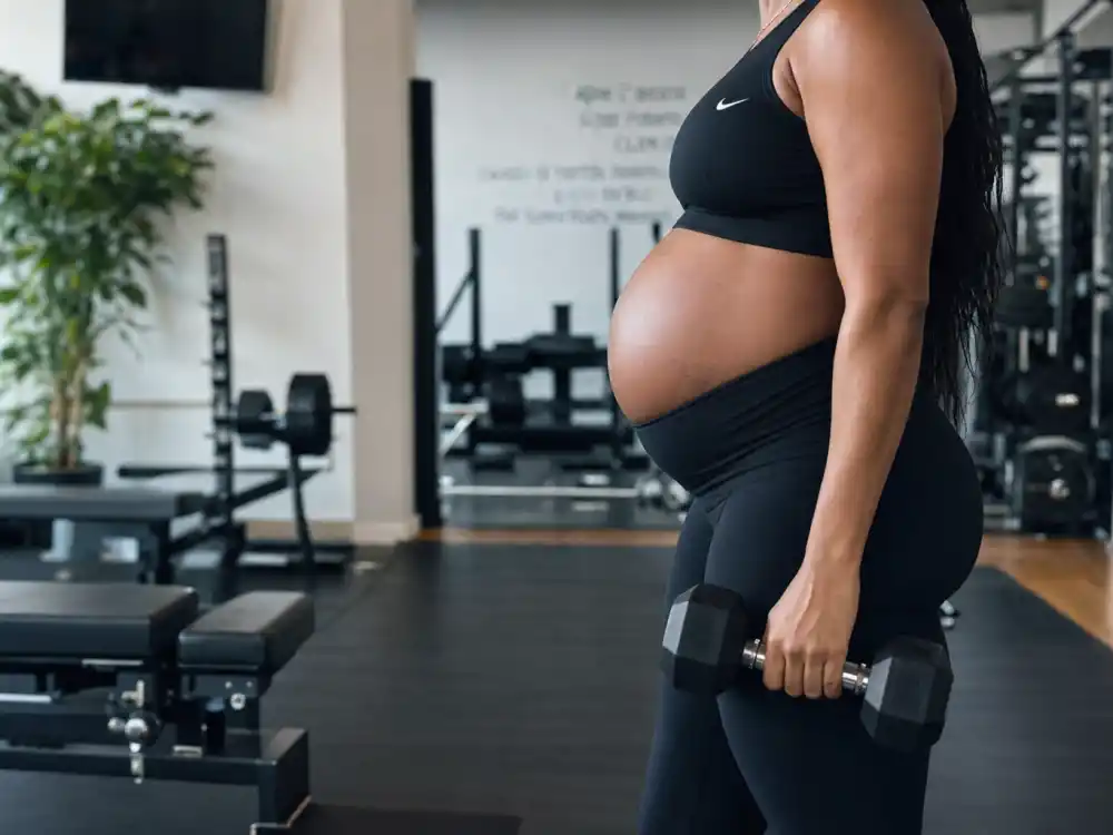 Anonymous athletic pregnant woman in Nike sports bra and leggings training in gym illustrating Serena Williams maternity fashion looks workout pregnancy style