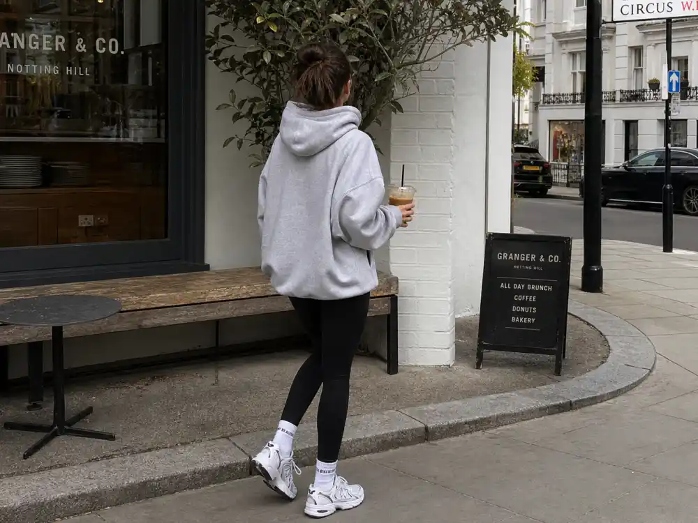 Grey hoodie black leggings and white sneakers on coffee run showing Sophie Turner off duty fashion athleisure morning formula
