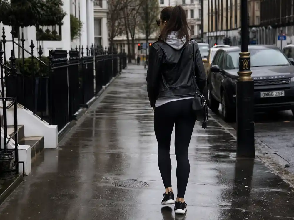Black leather moto jacket over grey hoodie and leggings illustrating Sophie Turner off duty fashion leather layering codes